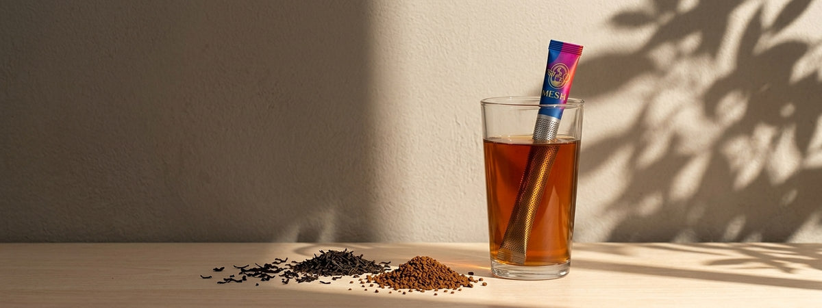 Bardakta demlenen Mesh Stick siyah çay, yanında çay yaprakları ve granül kahve