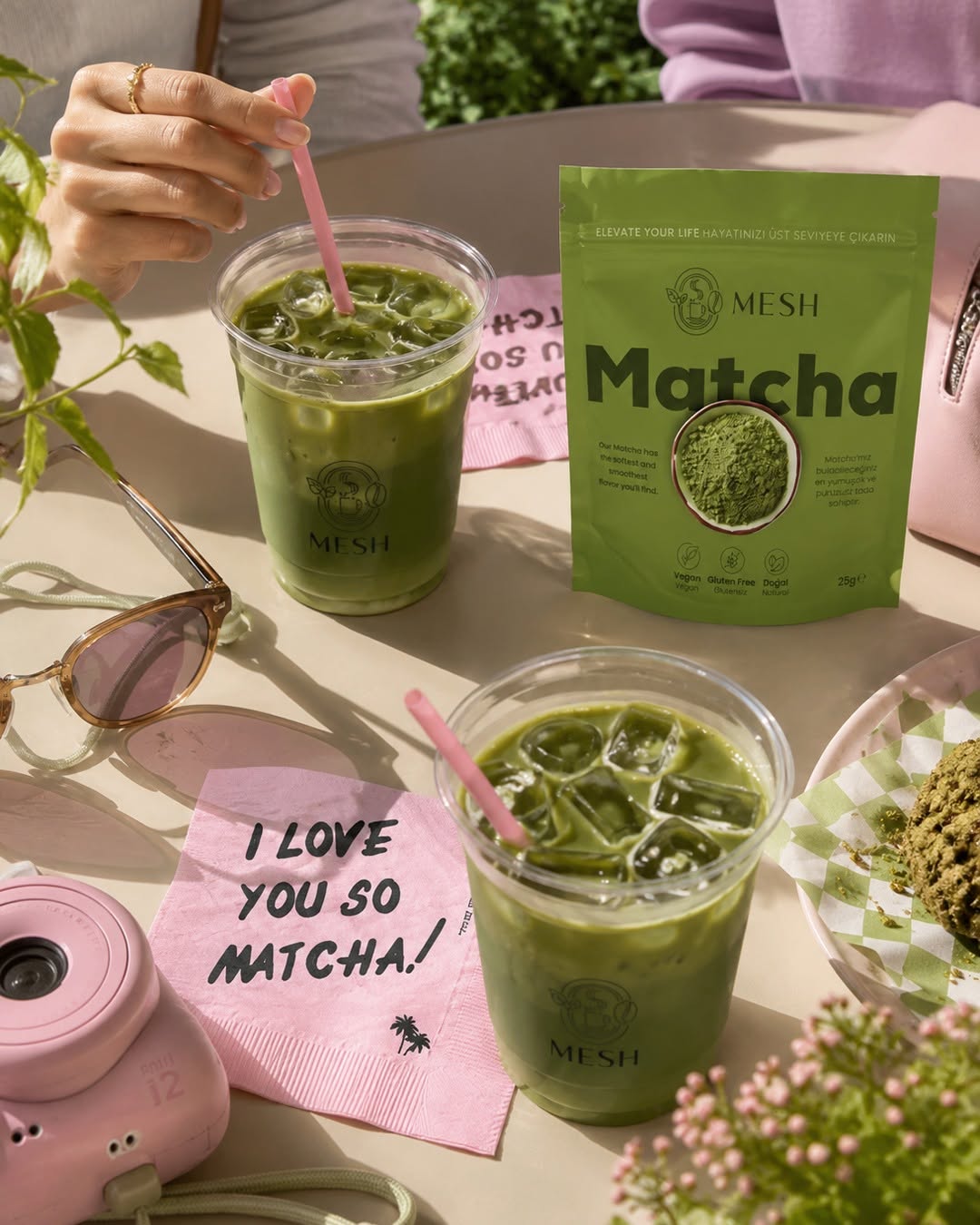 Buzlu matcha dolu iki bardak, yanlarında Mesh Matcha poşeti