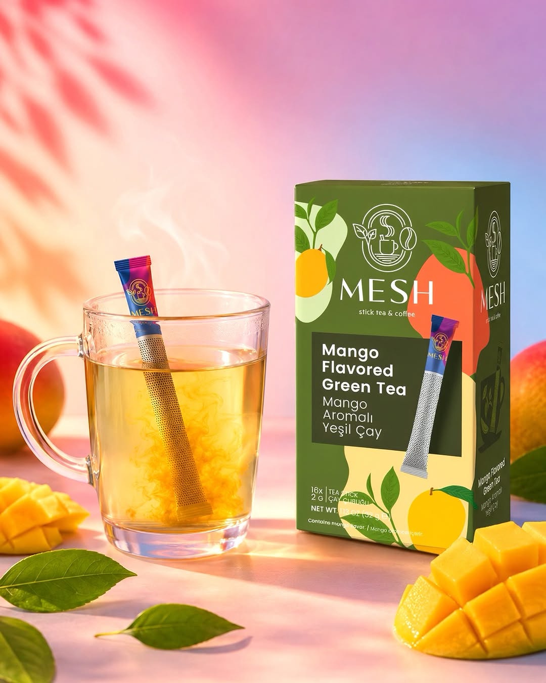 Cam fincanda mango aromalı yeşil çay, yanında mango dilimleri ve kutusu